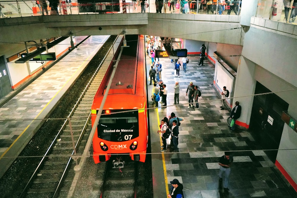 people walking on sidewalk near red bus during daytime