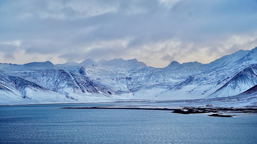 snow covered mountain near body of water during daytime