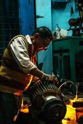 A technician repairing a generator with tools in a workshop.