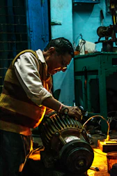 Mechanic replacing worn-out parts on a bulldozer under bright workshop lights.