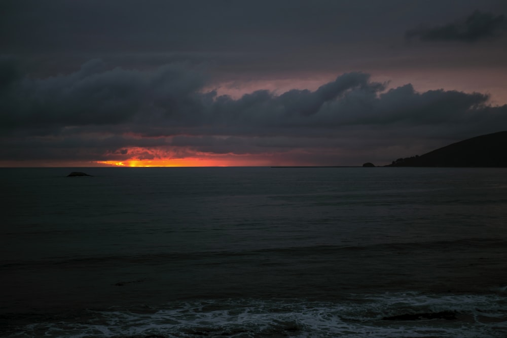 body of water under cloudy sky during sunset