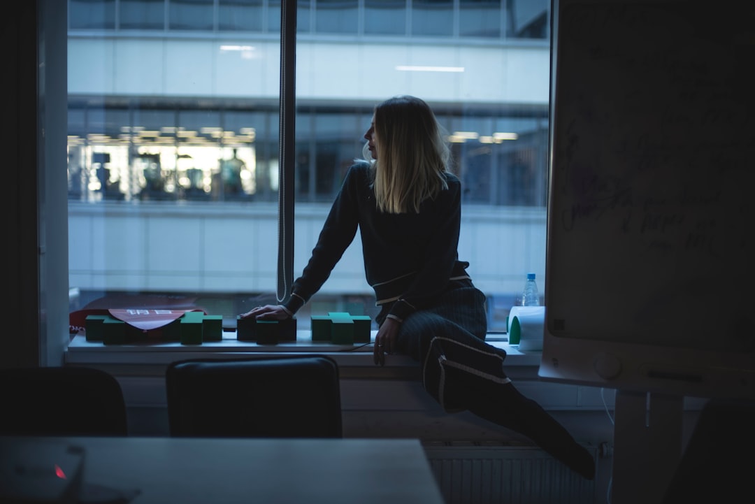 woman in black long sleeve shirt and blue denim jeans sitting on window during daytime