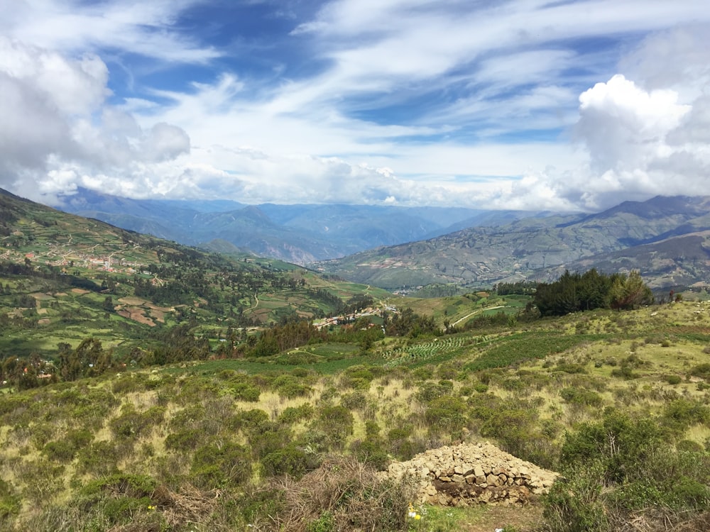 green trees on mountain under white clouds and blue sky during daytime