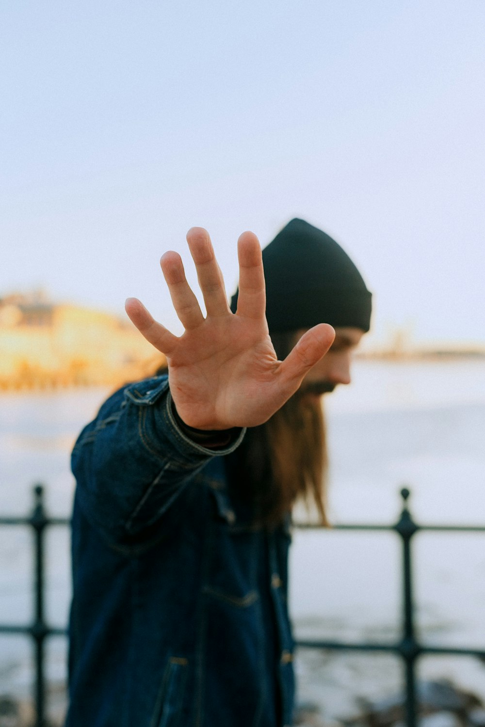 person in blue denim jacket holding black cap