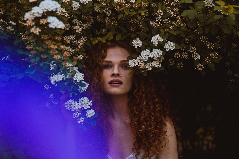 woman in purple tank top standing beside white flowers