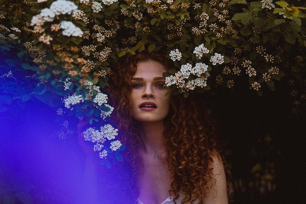 Frau im lila Tanktop steht neben weißen Blumen