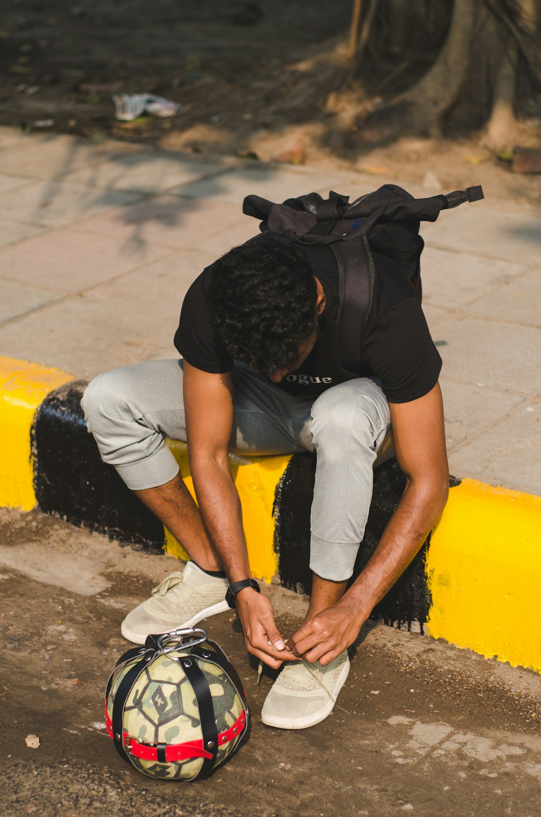 man in black t-shirt and gray shorts sitting on yellow plastic chair