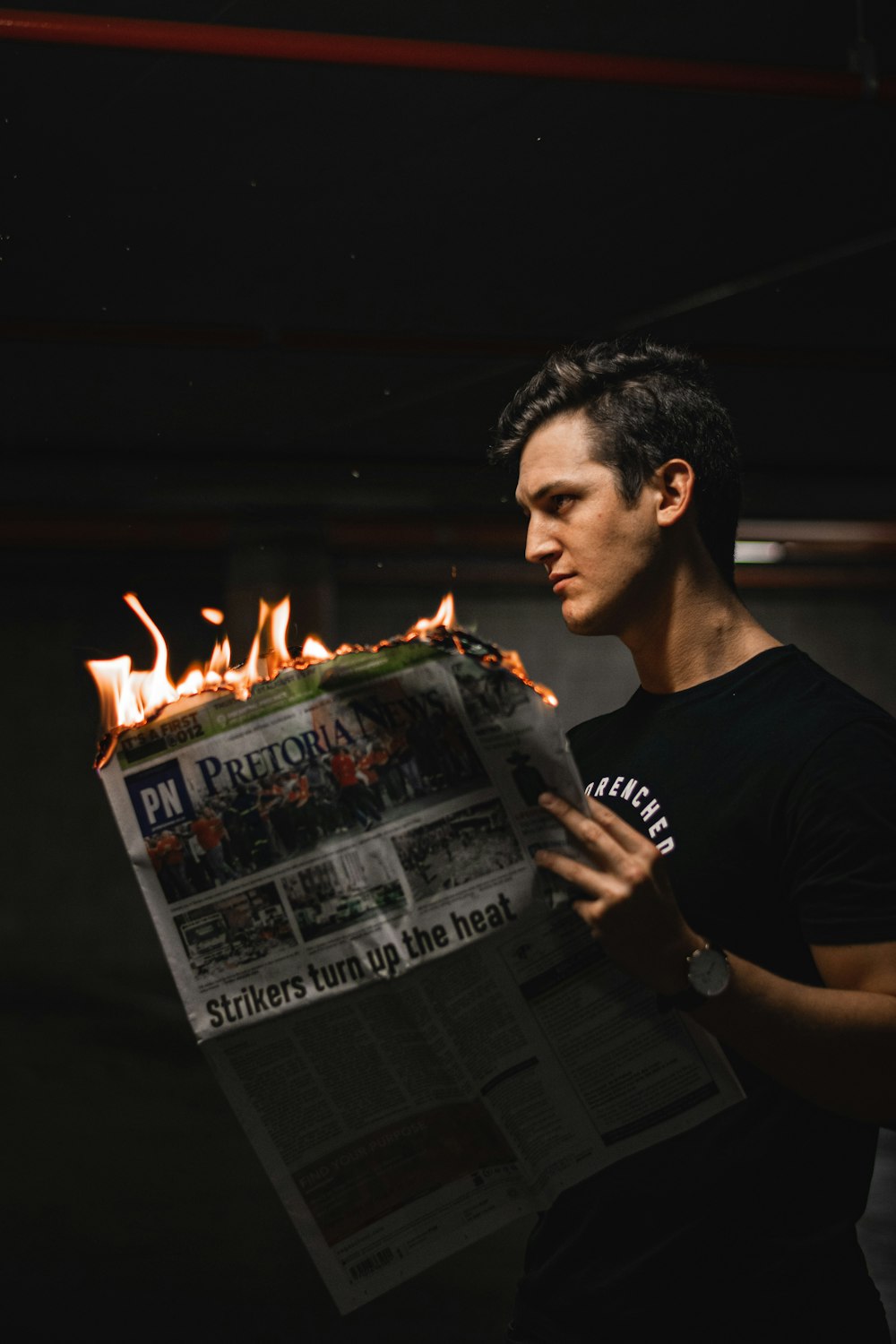 man in black crew neck t-shirt holding newspaper