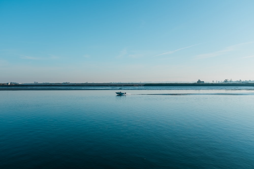 white boat on sea under blue sky during daytime