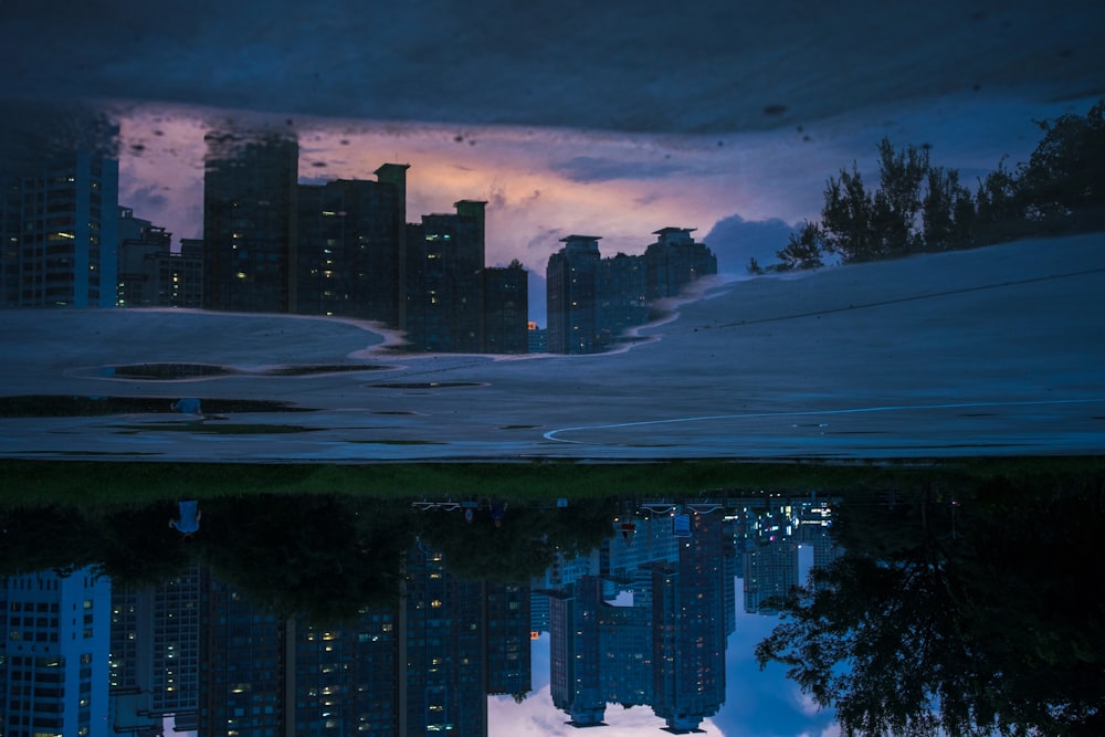 high rise buildings near body of water during night time