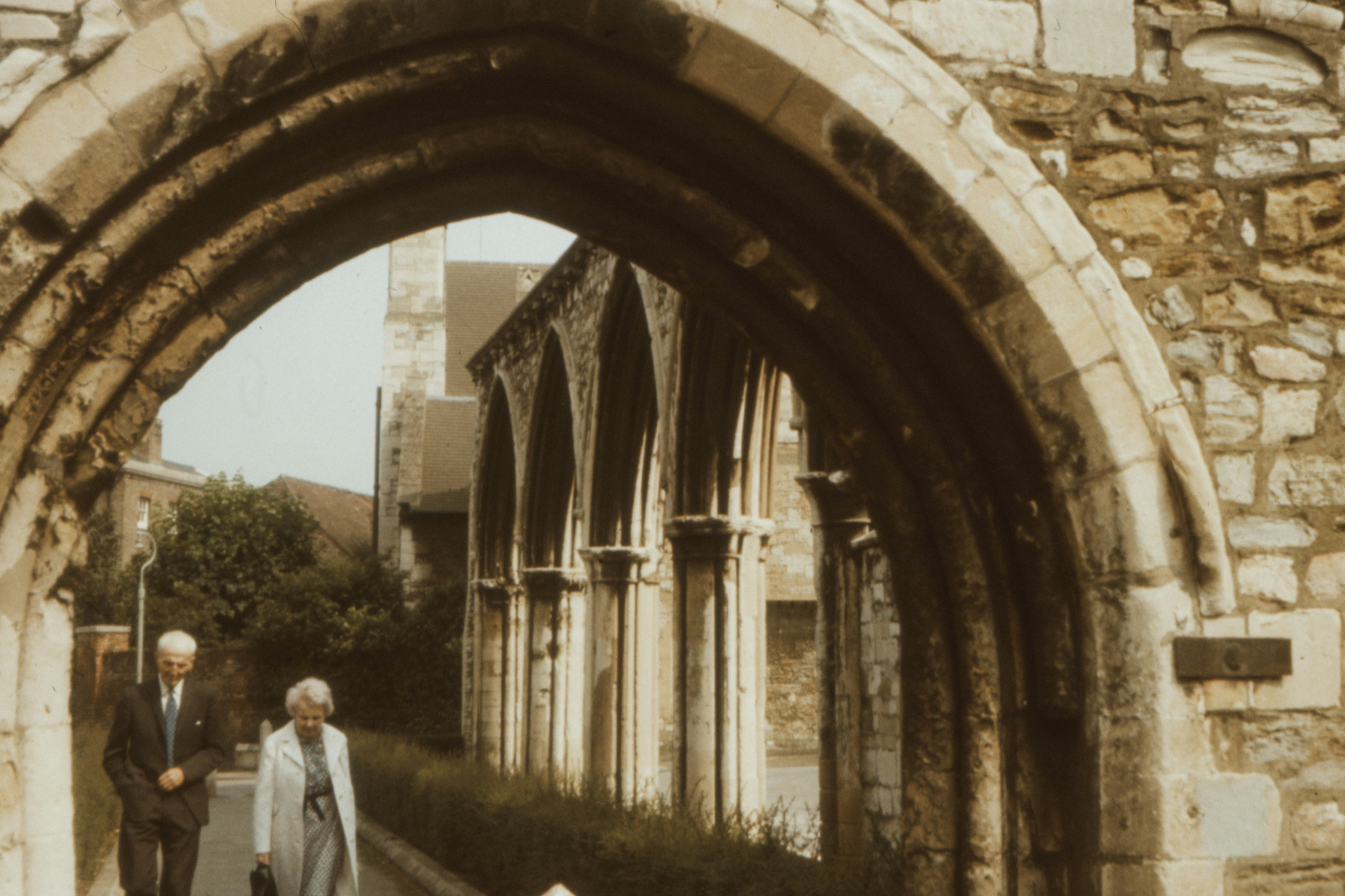 man in white suit standing near brown arch gate during daytime