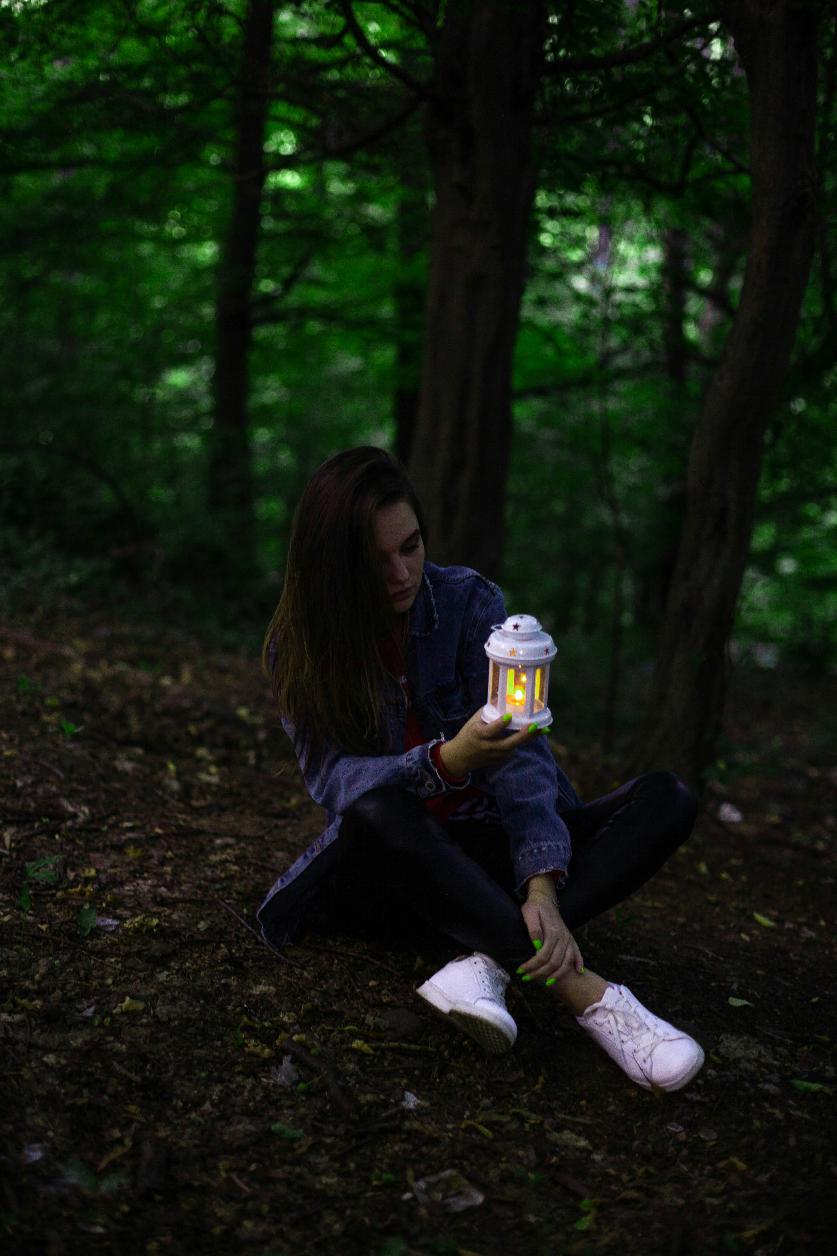 woman in black jacket sitting on ground with yellow liquid in clear glass jar