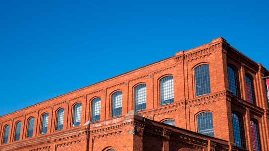 brown concrete building under blue sky during daytime in Manufaktura Shopping Mall Poland