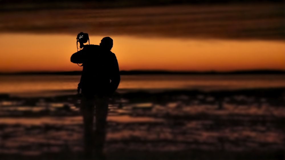 silhouette of 2 person on water during sunset