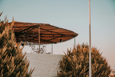 Modern metal pergola installed over a residential patio under a clear sky.