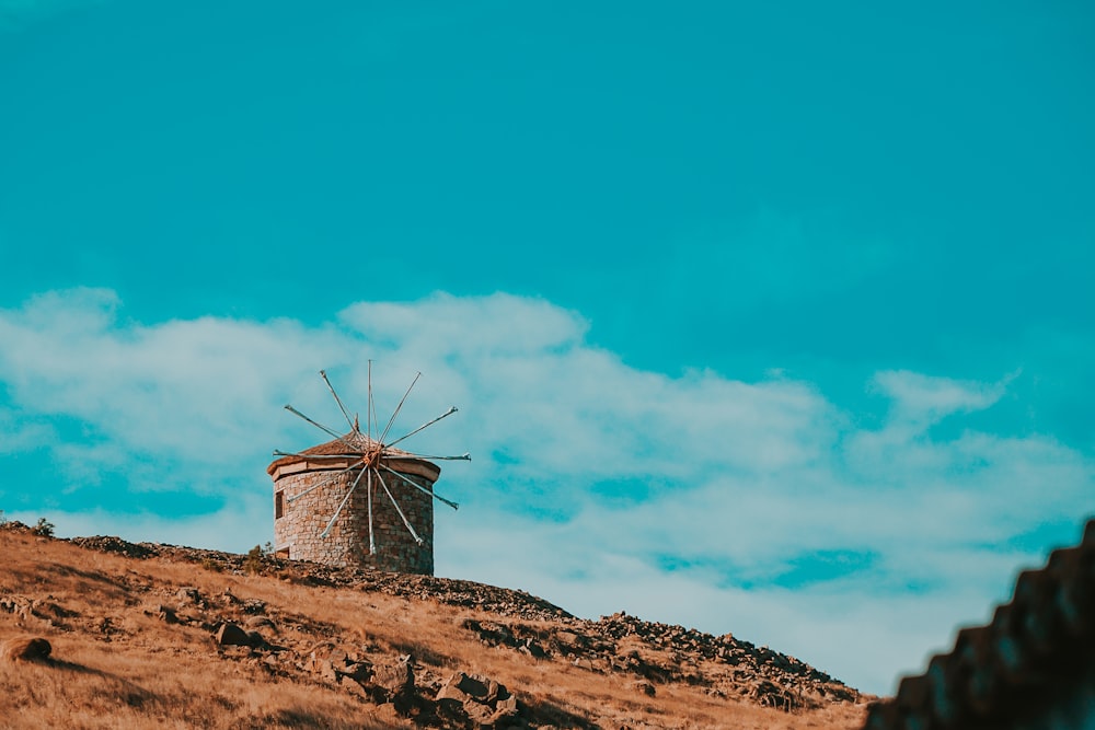 moinho de vento de madeira marrom no campo marrom sob o céu azul durante o dia