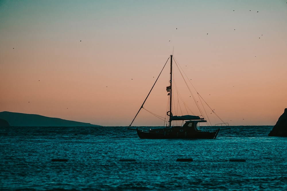 Silhouette des Segelboots auf See bei Sonnenuntergang