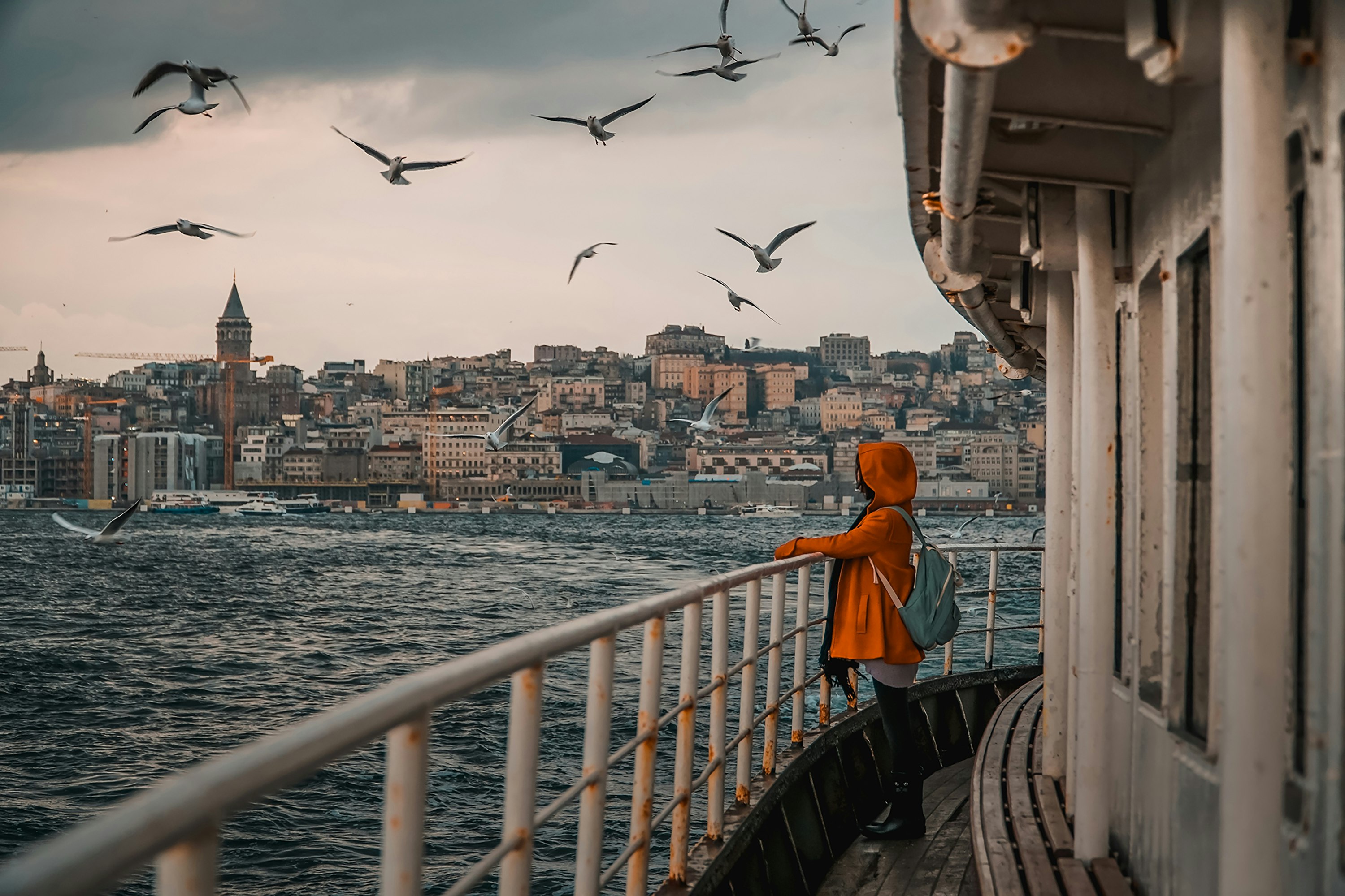 woman in orange hoodie standing on bridge during daytime