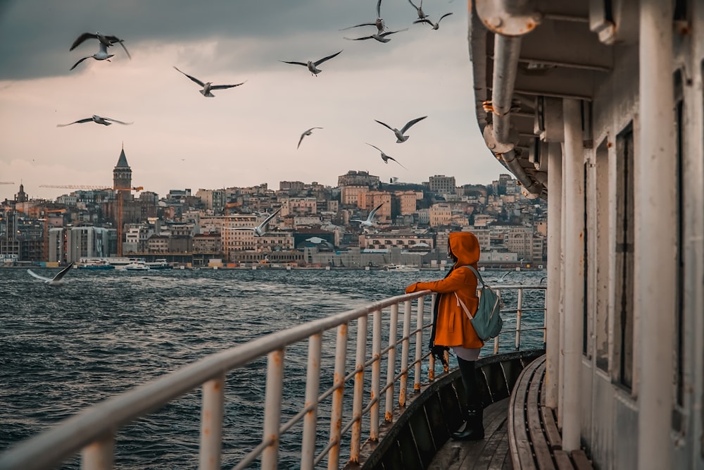 woman in orange hoodie standing on bridge during daytime