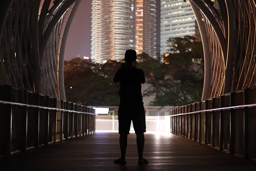 man in black jacket standing on brown wooden bridge during daytime