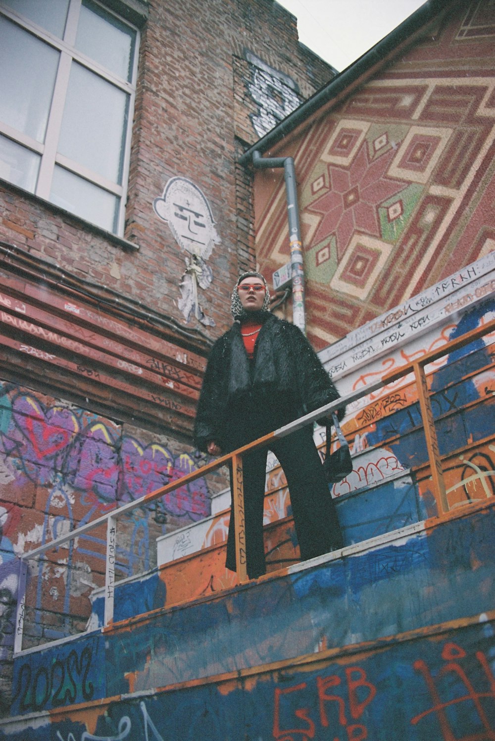 man in black coat standing beside brown wooden fence