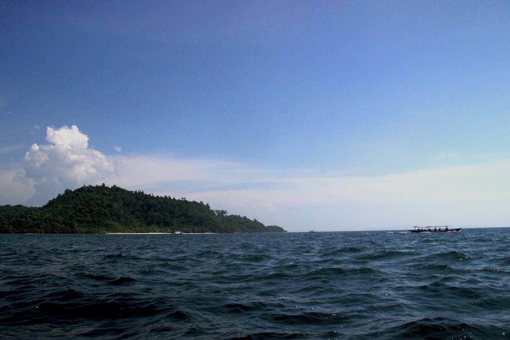 green island on blue sea under blue sky during daytime