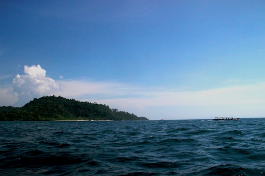 green island on blue sea under blue sky during daytime in West Sumatra Indonesia
