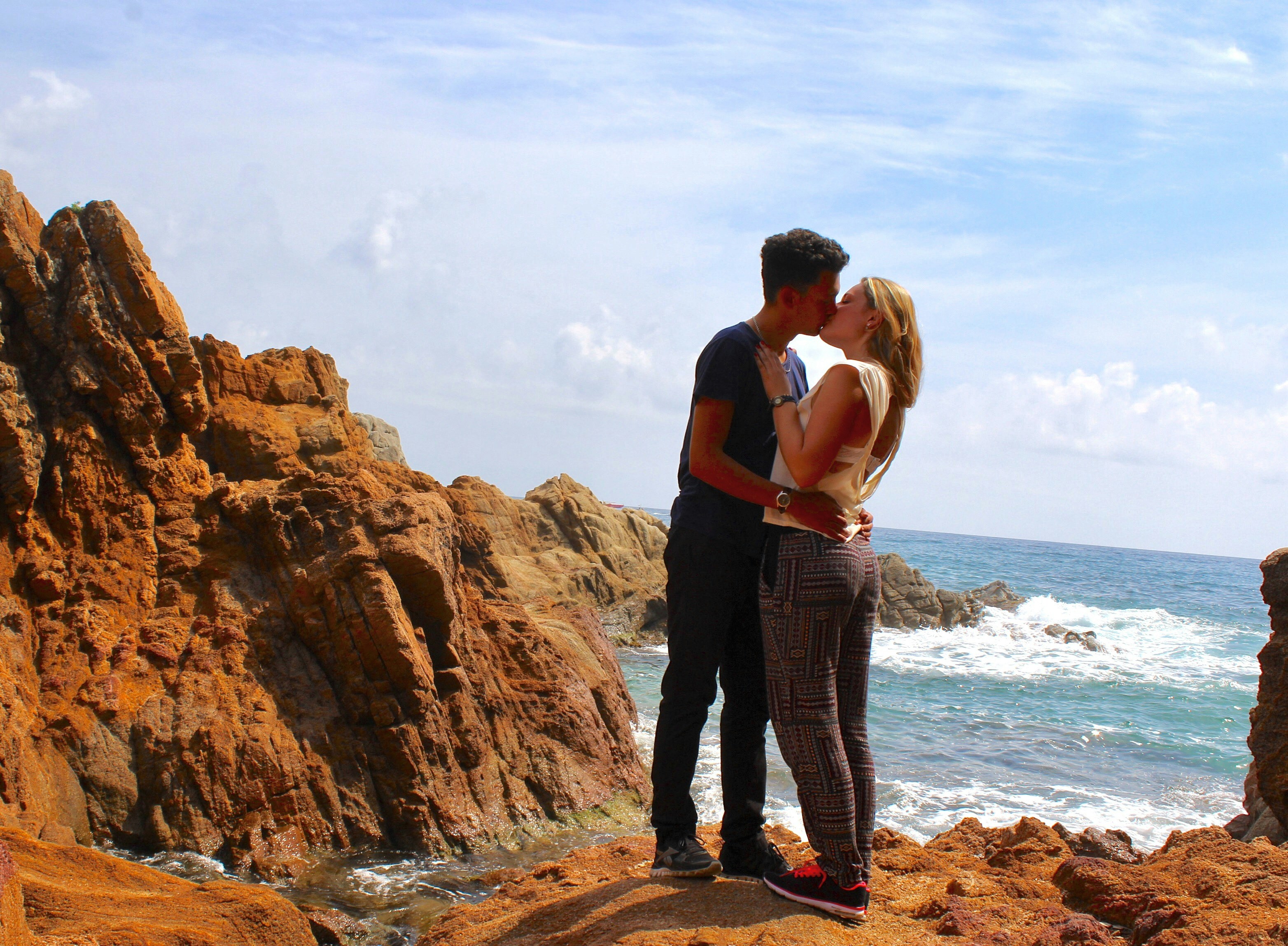man in black t-shirt and blue denim jeans standing on brown rock formation near body