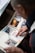 A person is looking through a scrapbook filled with various photographs and newspaper clippings. The pages have colorful paper corners holding the items in place. The images depict different scenes and articles.