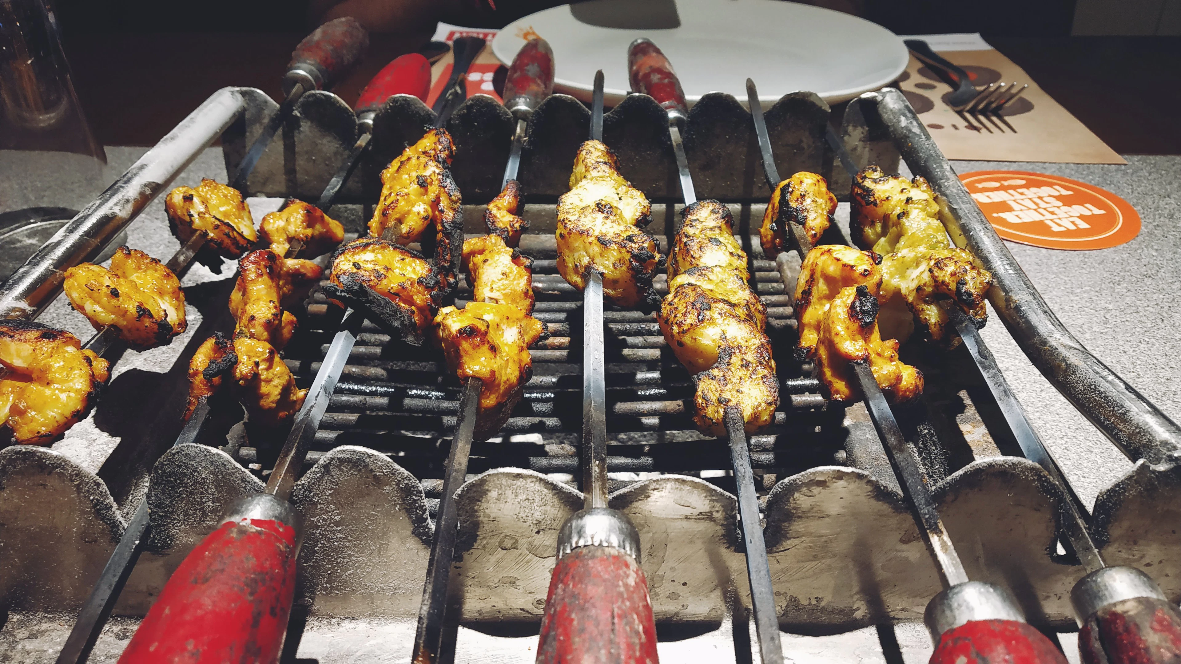 Skewered meat grilling over charcoal