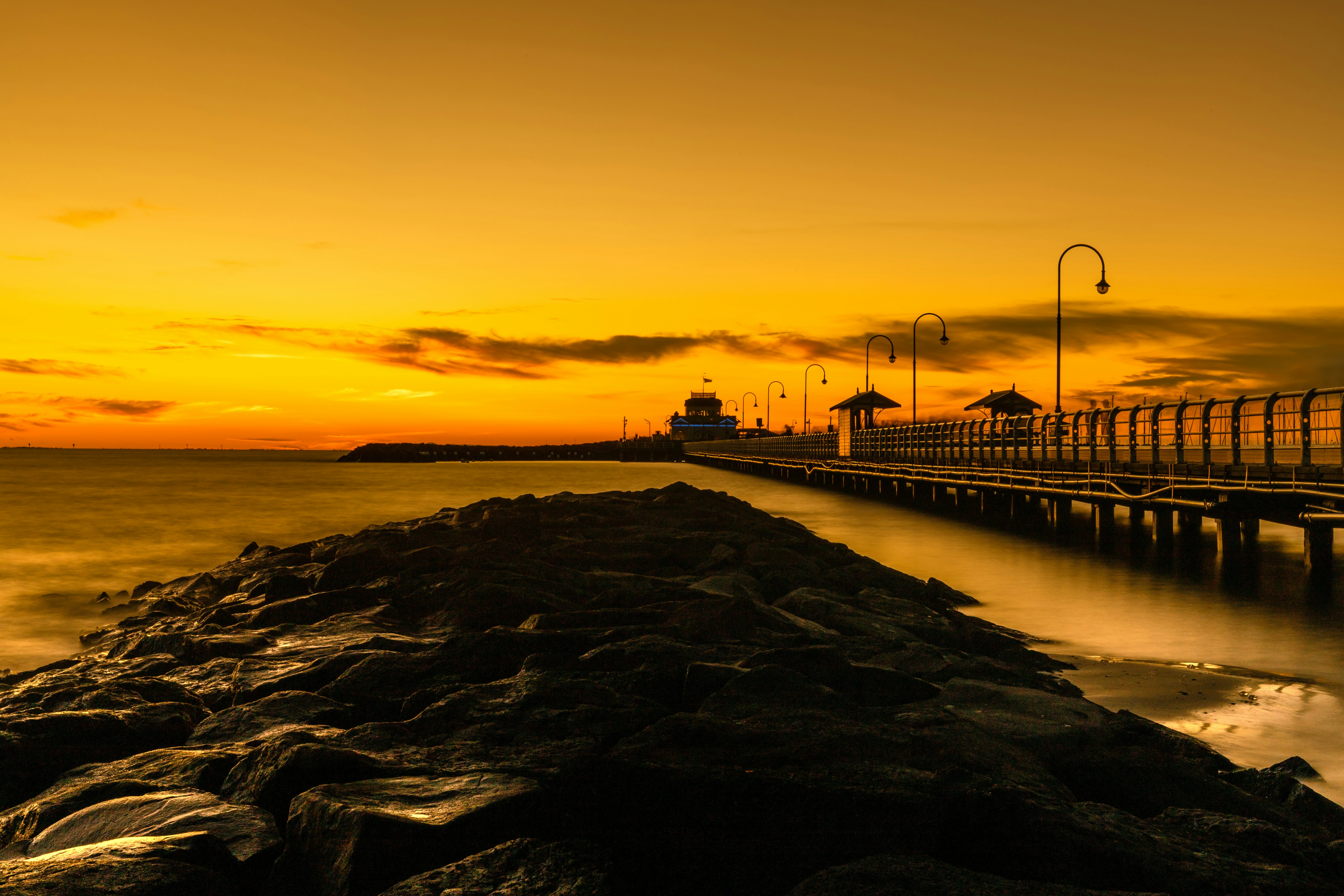 silhouette of bridge on sea during sunset