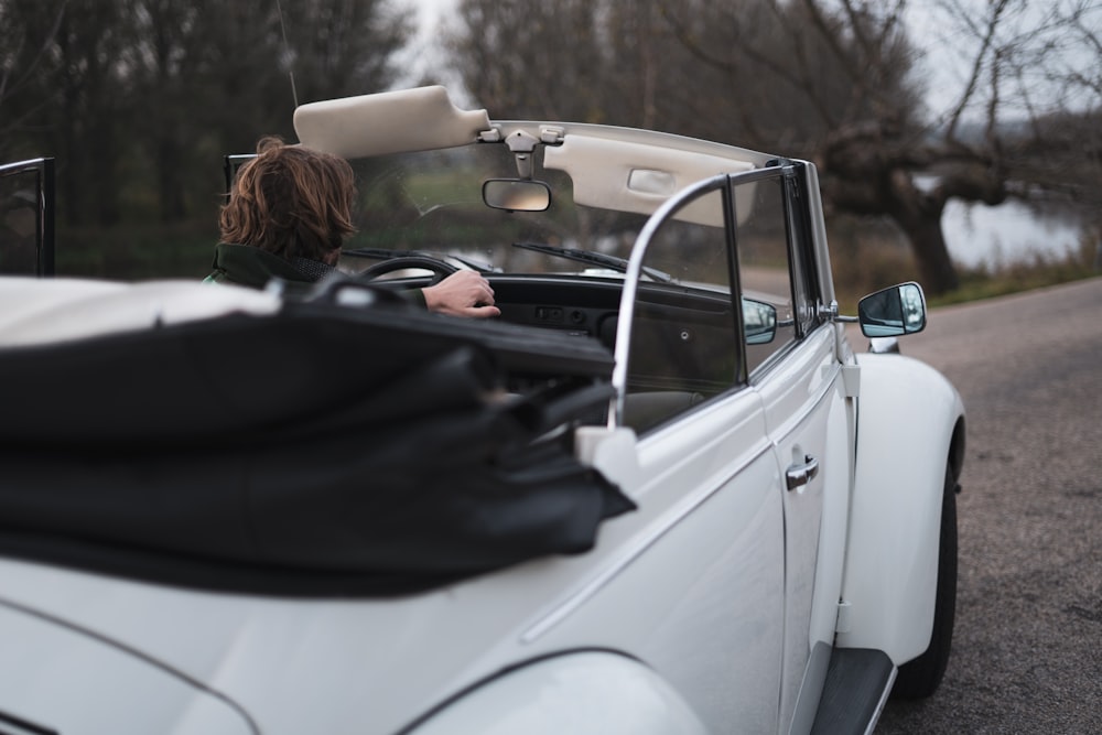 woman in black jacket driving white car during daytime