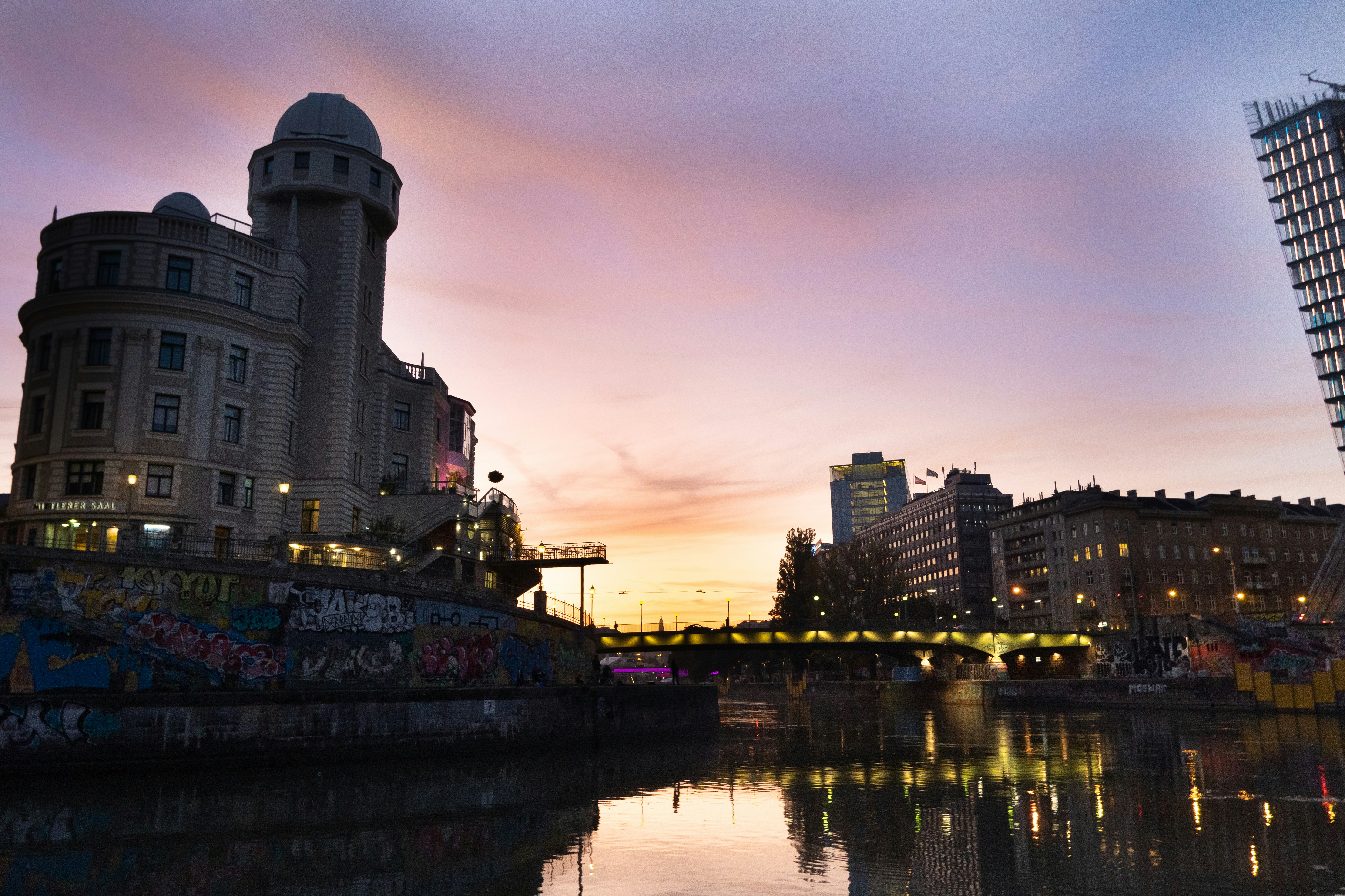 body of water near buildings during sunset