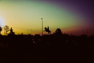 Sunset over the rodeo grounds with silhouettes of riders and horses preparing for the next event.