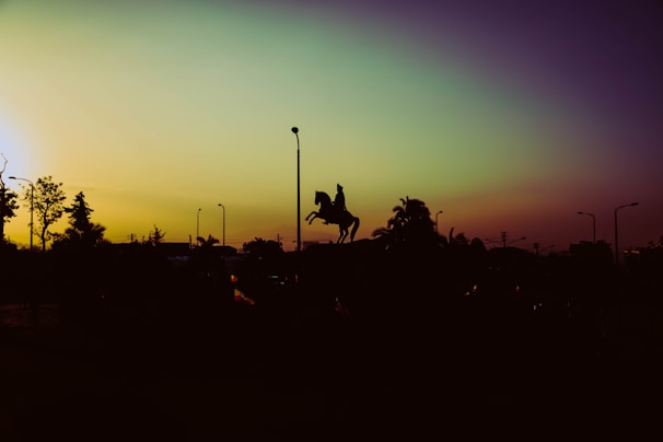 Sunset over the rodeo grounds with silhouettes of riders and horses preparing for the next event.
