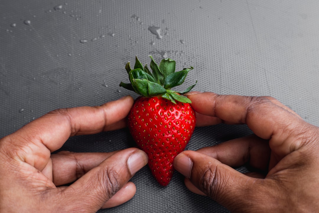 person holding red strawberry fruit