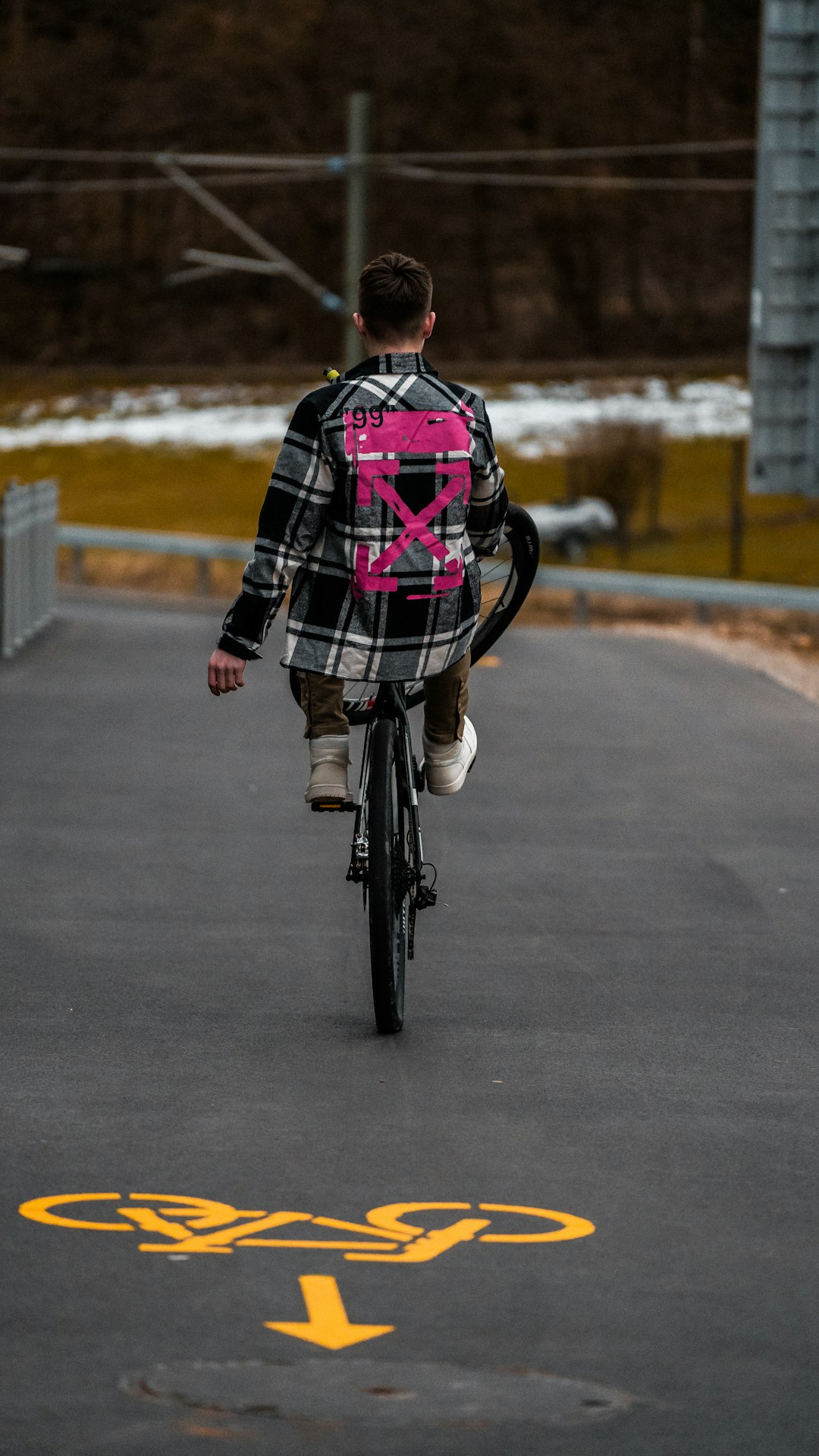 person in black and red plaid dress shirt riding bicycle on road during daytime