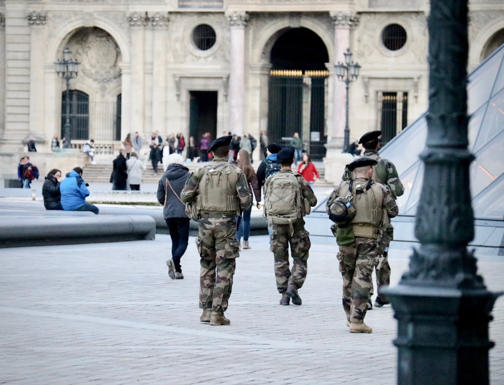 Soldats en uniforme de camouflage vert et marron debout sur un sol en béton gris pendant la journée