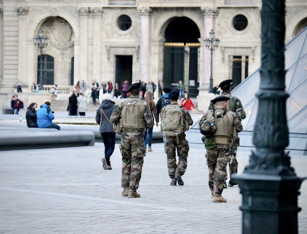 soldati in uniforme mimetica verde e marrone in piedi sul pavimento di cemento grigio durante il giorno