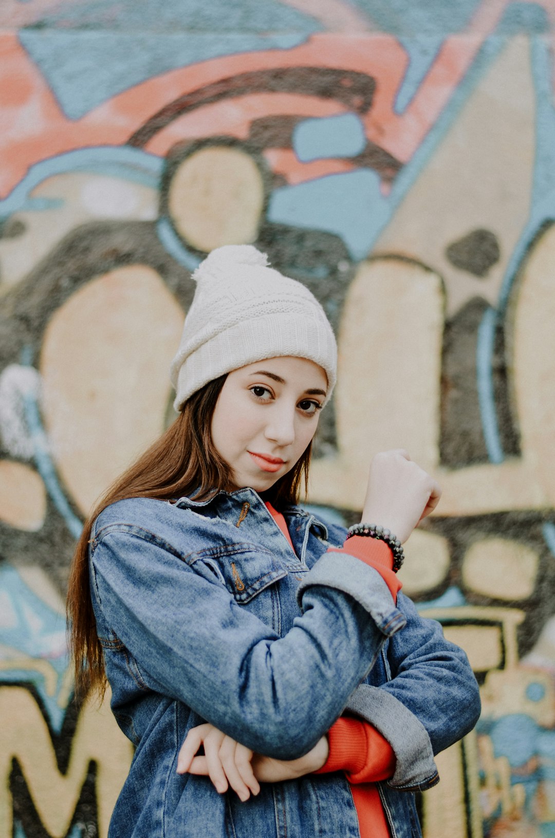 girl in blue denim jacket and white knit cap holding white cup