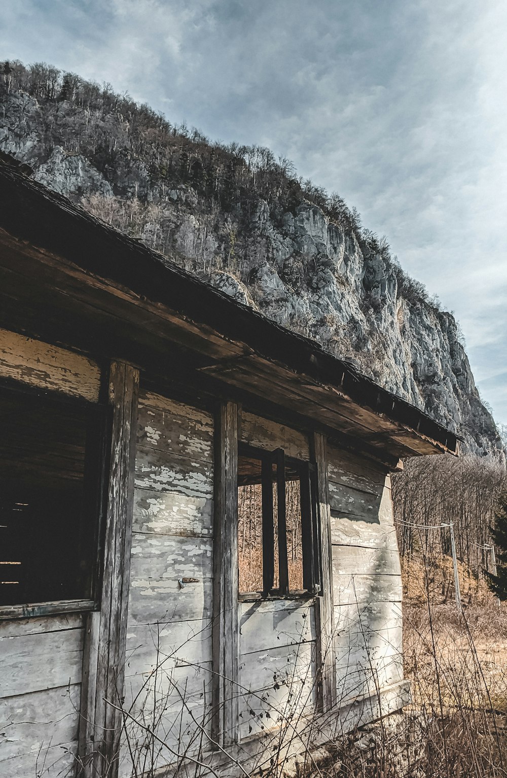 brown wooden house near gray rocky mountain under white cloudy sky during daytime