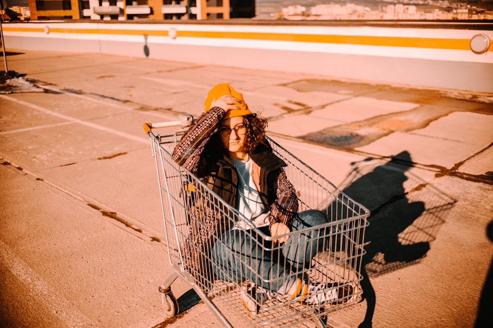 woman in gray jacket and yellow scarf riding on shopping cart