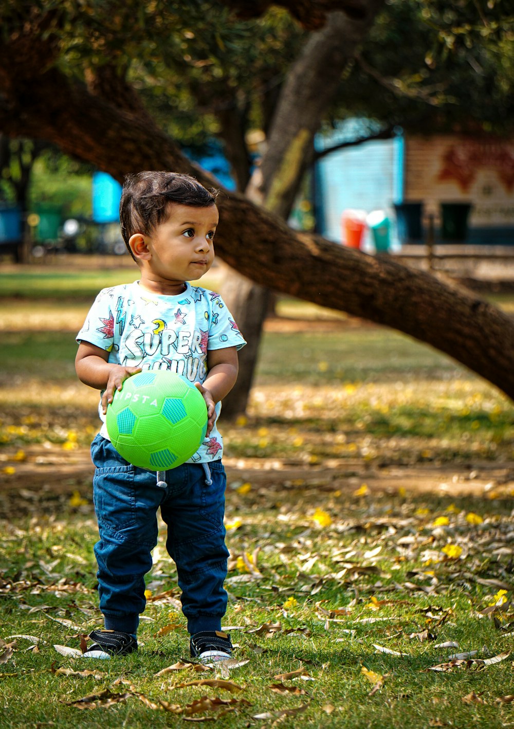 boy in white t-shirt and blue denim jeans standing on green grass field during daytime