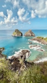 brown rock formation on sea under blue sky during daytime