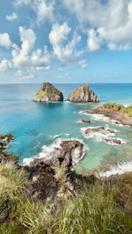 brown rock formation on sea under blue sky during daytime