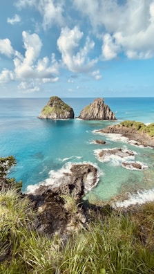 brown rock formation on sea under blue sky during daytime