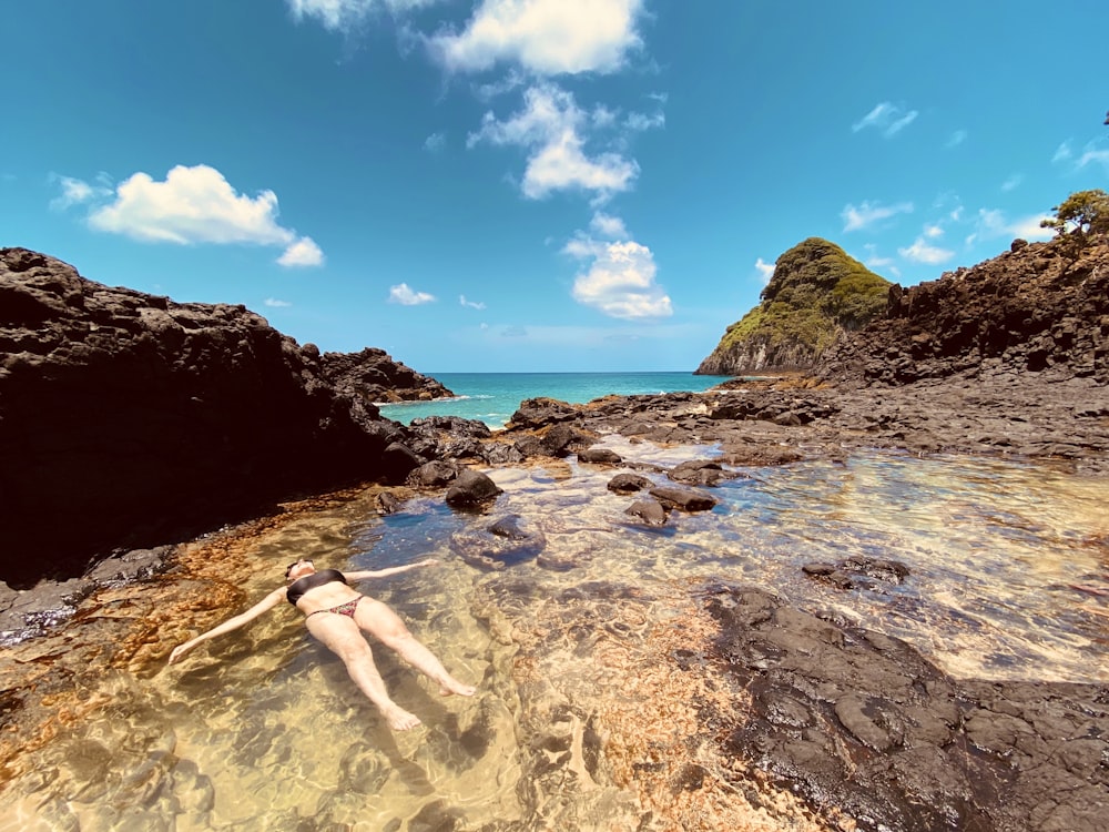 Mujer en bikini blanco acostado en la orilla de la playa durante el día