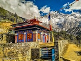 brown and white concrete building near mountain under white clouds and blue sky during daytime