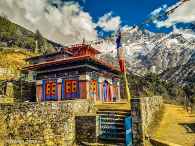 brown and white concrete building near mountain under white clouds and blue sky during daytime