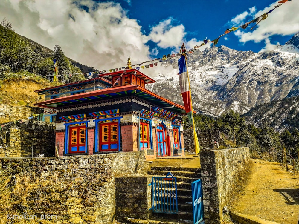 brown and white concrete building near mountain under white clouds and blue sky during daytime